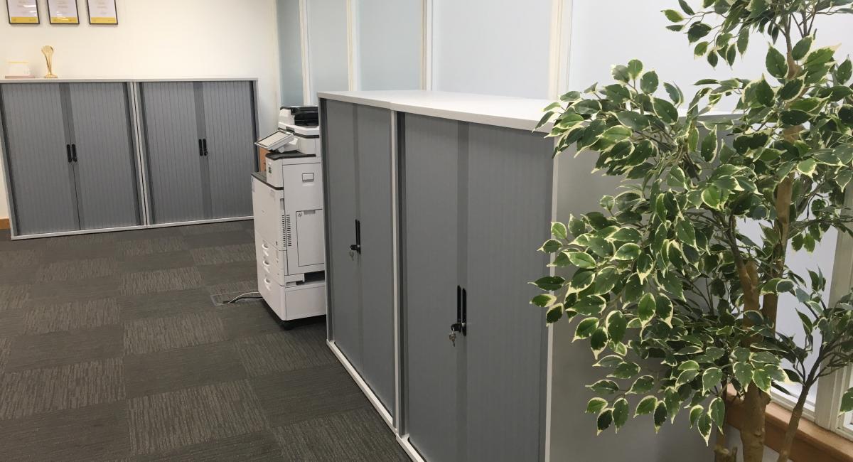 White storage cuboards with silver, side opening and lockable tambour doors.