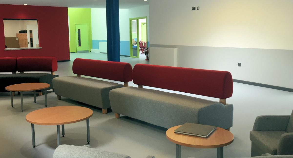 Breakout space furniture including grey and burgundy sofas and loose furniture.