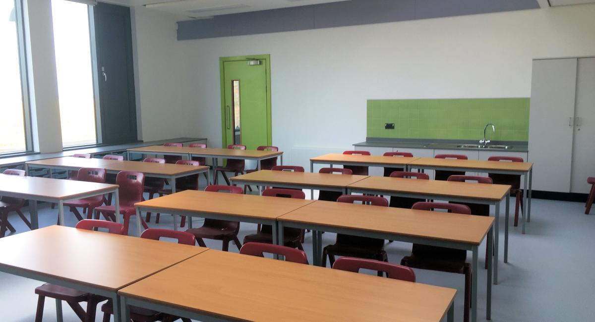Beech fully welded classroom tables, partnered with red one piece Postura+ classroom chairs.